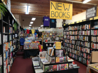 Inside News From Nowhere Bookshop, including: shelves of books along the walls, book displays, tshirts hanging up